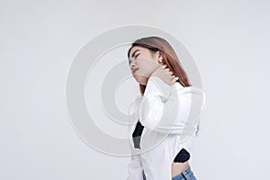 A pained young woman with tilted head holding her stiffed neck in pain. Isolated on a white background