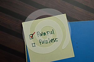 Painful and Painless write on sticky notes and supported by additional services write on a sticky notes isolated on Wooden Table