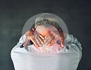 Painful sensations. Studio shot of a mature man experiencing neck ache against a black background.