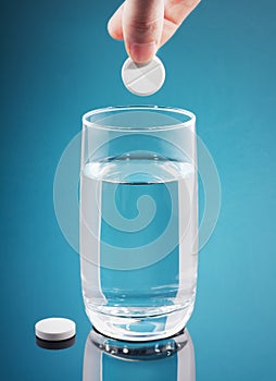 Painkiller tablet in glass of water with bubbles photo