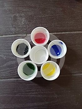 Paint botals caps on the wooden table in flower Pattern colourful red white black blue green and yellow bird eye view