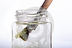 Paint brush in a can and a cloud of paint in water. White background.