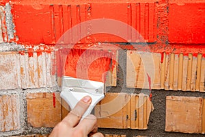 Paint brush with red color on brick wall