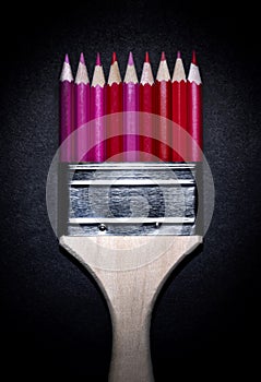 Paint brush with red colored pencils.