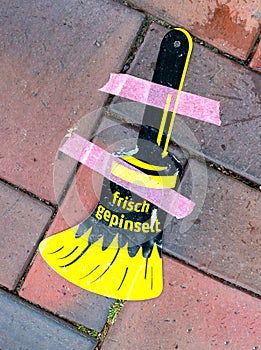 Paint brush symbol on a sidewalk for freshly painted objects. Text: freshly painted - frisch gestrichen photo