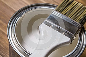 Paint brush on a tin can with white paint close-up