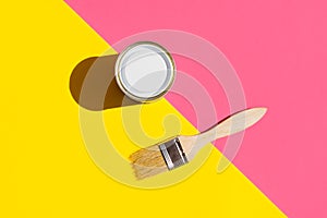 Paint brush with wooden handle can of varnish on trendy duotone pink yellow background. Interior design home refurbishing fashion photo