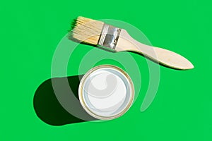 Paint brush with wooden handle can of varnish on trendy green background. Interior design home refurbishing fashion concept