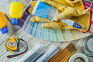 Paint brush in working gloves with any other construction tools on white wood boards