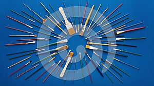 Paint brushes in circular burst pattern. Flat lay shot, blue background. 4k loop