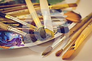 Paint brushes and a palette lie on the table, close-up