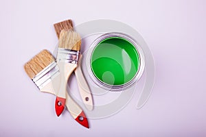 Paint brushes placed on top of can filled with green paint