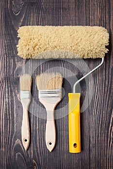 Paint brushes and roller on old wooden background