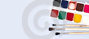 Paint brushes with used watercolor paint palette on canvas overhead view