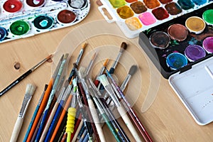 Paint brushes and watercolor paints,  tempera paints on the table in a workshop