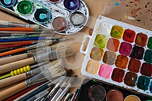 Paint brushes and watercolor paints,  tempera paints on the table in a workshop