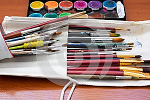 Paint brushes and watercolor paints, tempera paints on the table in a workshop