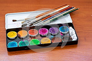 Paint brushes and watercolor paints, tempera paints on the table in a workshop