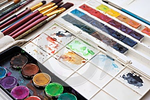 Paint brushes and watercolor paints, tempera paints on the table in a workshop