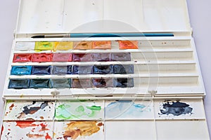 Paint brushes and watercolor paints, tempera paints on the table in a workshop