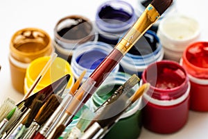 Paint brushes and watercolor paints, tempera paints on the table in a workshop