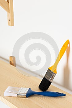 Paint brushes are on a wooden shelf