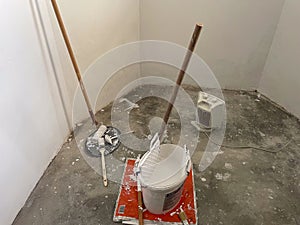 Paint bucket with brush and white paint in a room during renovation