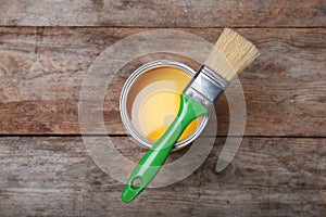 Paint can and brush on wooden background