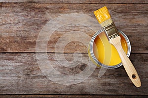 Paint can and brush on wooden background, top view