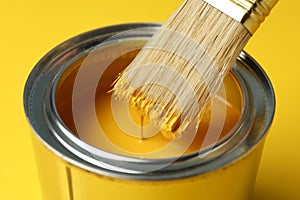 Paint can and brush on yellow background