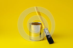 Paint can and brush on yellow background