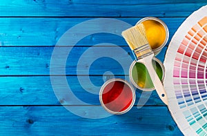 Paint cans color palette, cans opened with brushes on blue table