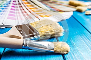 Paint cans color palette, cans opened with brushes on blue table