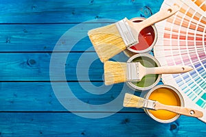 Paint cans color palette, cans opened with brushes on blue table