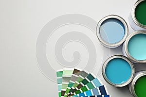 Paint cans and color palette on white background, top view.