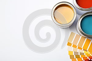 Paint cans and color palette on white background, top view.