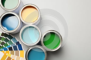 Paint cans and color palette on white background, top view.