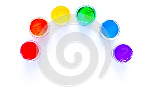 The paint cans are displayed in a semicircle in the form of a rainbow on a white background. top view, flat lay, copy