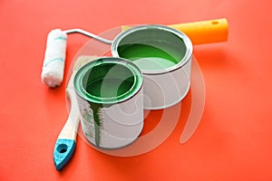 Paint cans with roller and brush on color background