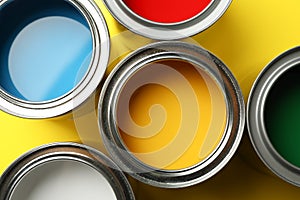 Paint cans on yellow background, top view