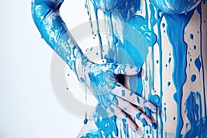 paint drips from the woman body, blue liquid drops on beautiful model girl`s body, creative abstract