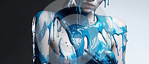 paint drips from the woman body, blue liquid drops on beautiful model girl`s body, creative abstract