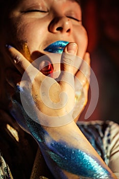 Paint on the face and body of a woman. A woman in the spotlight poses for the camera. Body art.