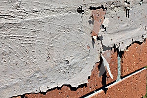 Paint flaking off a red brick wall