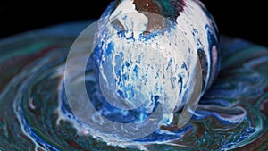 Paint flows down the surface of the texture ball and spreads over the table.