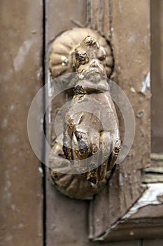 Paint peeling door knocker on worn door of dilapidated house