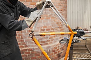 Paint removal: man using steel wool over a bike frame after using a blowtorch