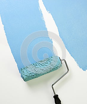 Paint roller applying blue paint photo