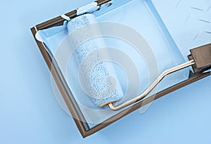 Paint roller with blue paint in tray