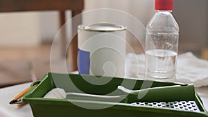 paint roller and bottle of solvent on table